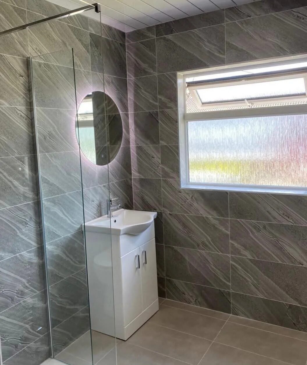 Walk-in shower installation in Dublin with large-format grey tiles and frameless glass screen