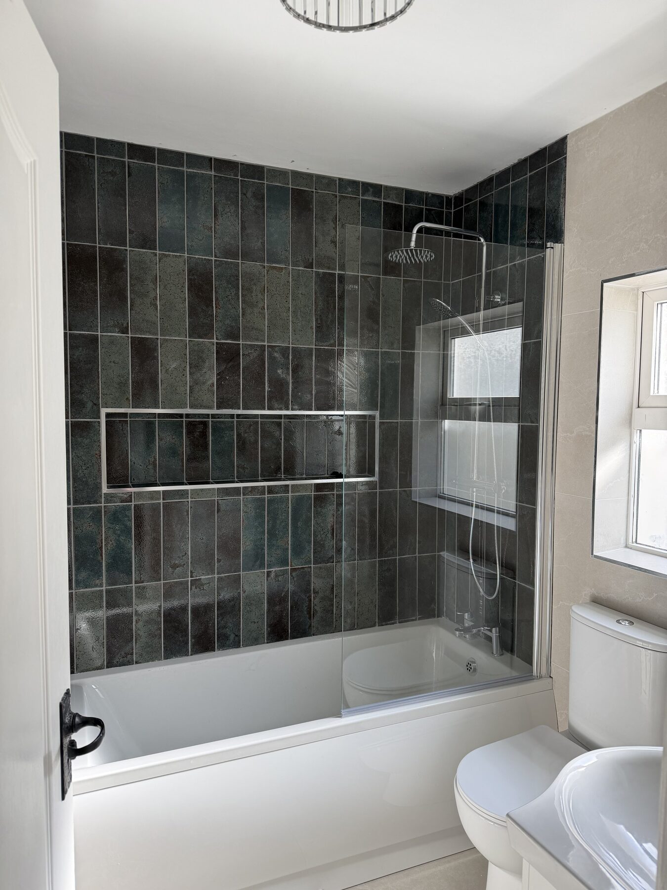 Family bathroom renovation in Dublin with deep green tiles, bath, shower and recessed niche by AJ Bathrooms